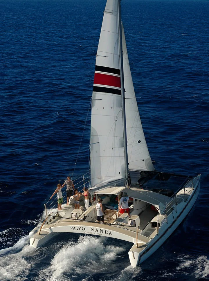 Hoʻo Nanea catamaran charter sailing off Oahu, Hawaii, with passengers enjoying the open ocean.